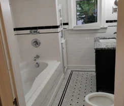 Freshly cleaned bathroom with white tile and black accents.