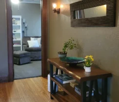 Clean and tidy hallway with a wooden floor leading to a small reading room.