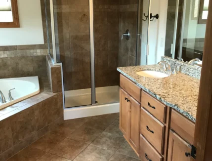 Deep cleaned bathroom with a hot tub, glass standing shower, and granite bathroom countertop.