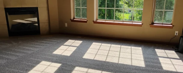 Clear vacuum lines on a gray carpet in a large living room after a move-out clean.