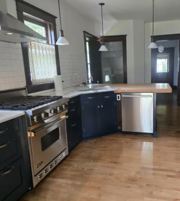 kitchen-after-cleaning-service A clean kitchen with blue cabinets and a stainless steel stove with gold accents after receiving cleaning service.