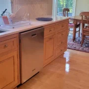 Shining wooden floor in a kitchen with wooden cabinets after a routine cleaning.