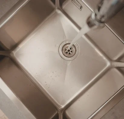 sink-running-water Inside a stainless steel sink with running water.