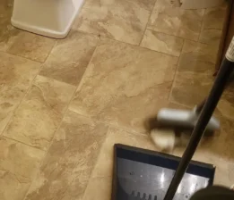 sweep-bathroom Sweeping debris in a bathroom for a move out deep cleaning service.
