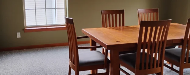 Tidy dining room with a gray carpet and brown wooden dining table, after a routine cleaning.