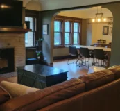 Tidy living room after a routine cleaning with a brick fire place and leather couch.