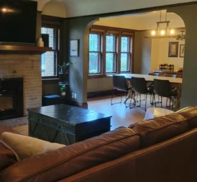 Tidy living room after a routine cleaning with a brick fire place and leather couch.