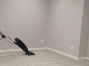 Zoom into MG's manager vacuuming gray carpet.